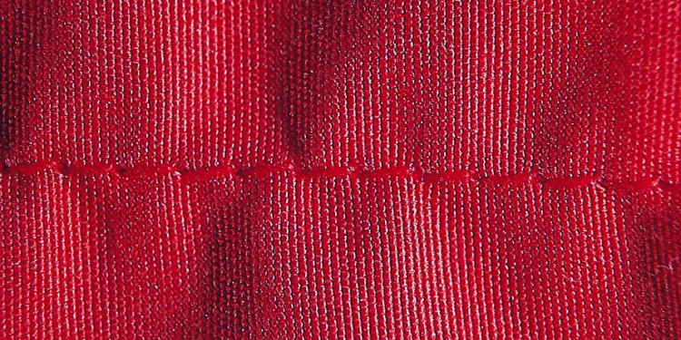 Close-up of a red fabric showing seam puckering
